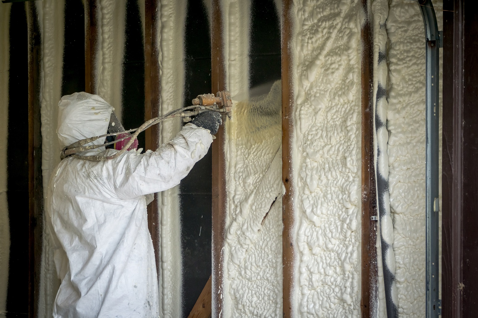 Brazos Thermal worker using tools to spray insulation foam in residential home build.