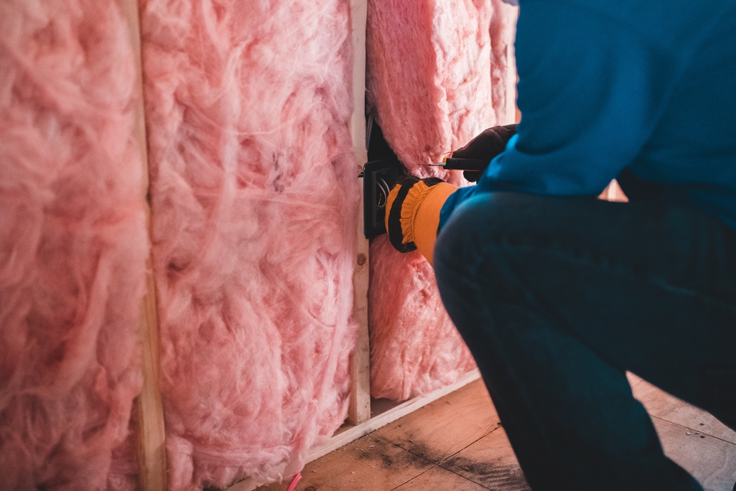 Up close image of a worker with protective gloves on installing insulation.