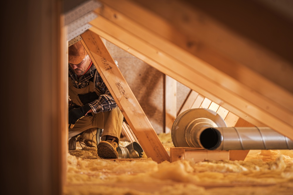 Brazos Thermal worker installing insulation in residential home attic.