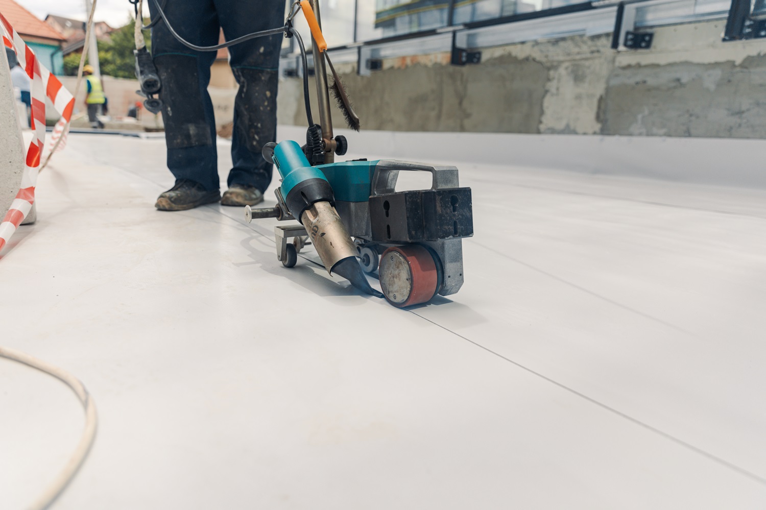 Brazos Thermal worker installing TPO roofing with tools.