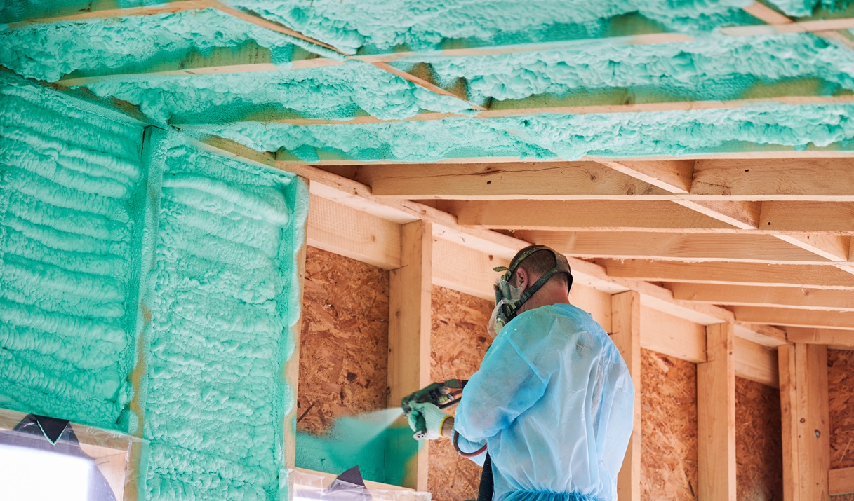 Up close shot of worker in protective gear using a tool to spray closed cell foam insulation.