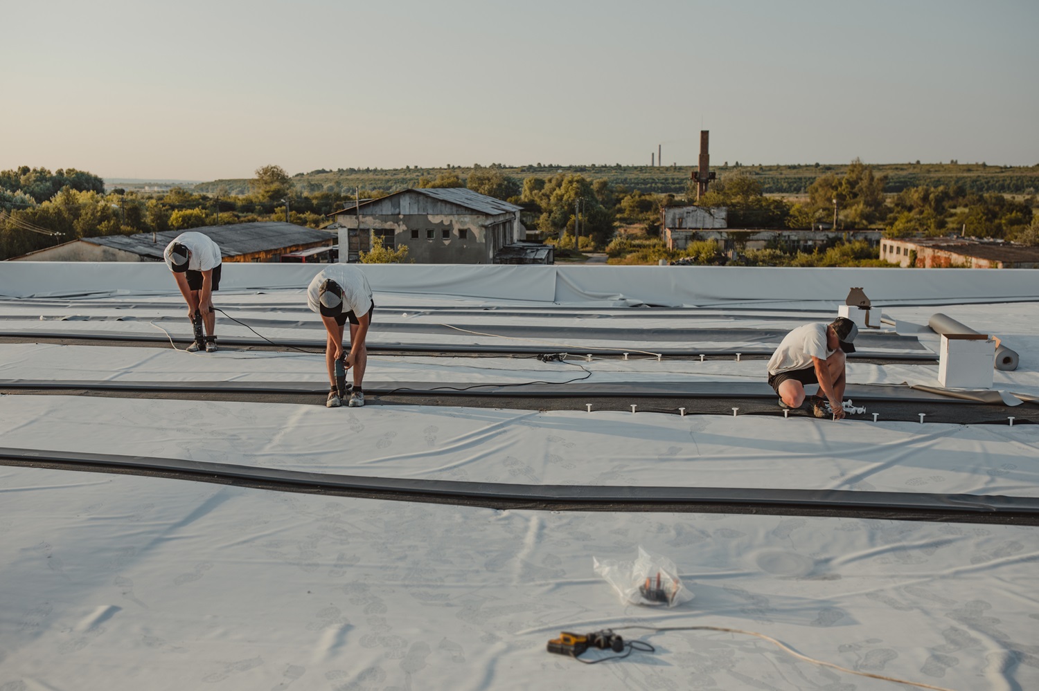 Brazos Thermal workers working on roof restoration with old buildings and landscapes in the background.