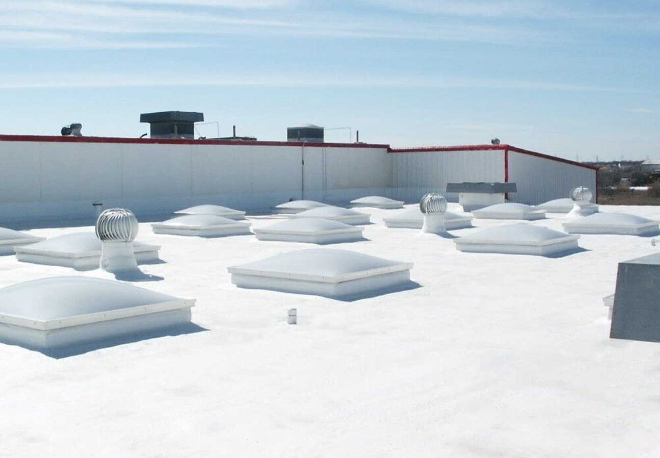 White industrial roof with sky light fixtures with the roof coated in high performance spray foam by Brazos Thermal.