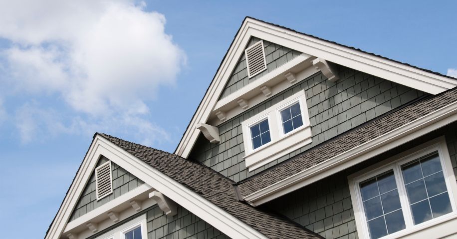 A low-angle view of a home with green siding and the sky.