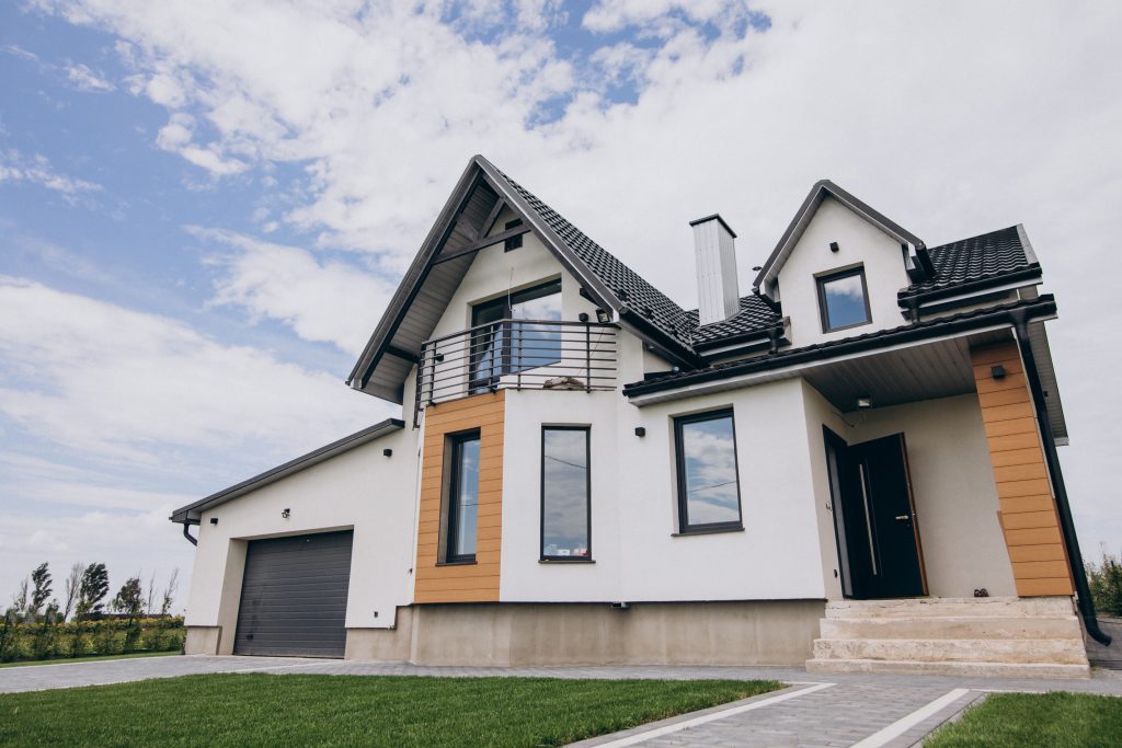 A white, modern house with black accents on a partly cloudy day.