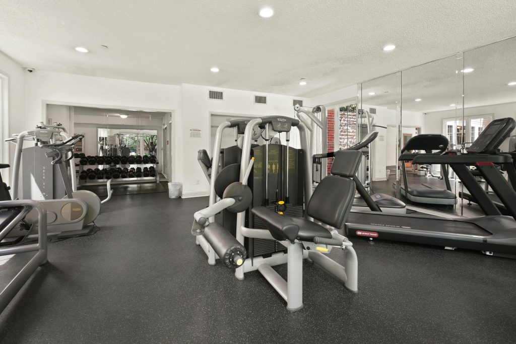 An empty gym with free weights, weight machines, and treadmills in it.