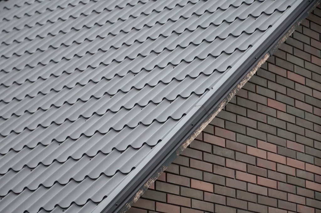 A close-up of the top of a brick building with a black, metal roof.