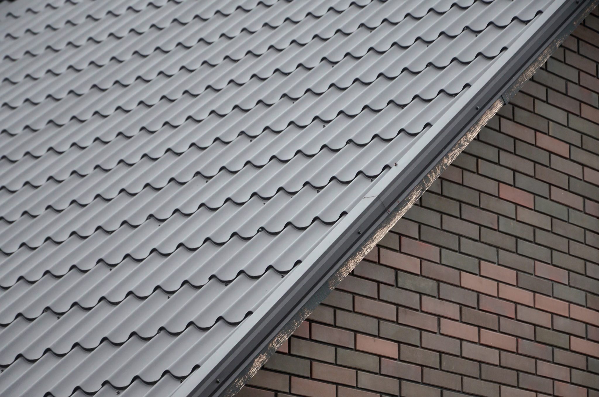 A close-up of the top of a brick building with a black, metal roof.
