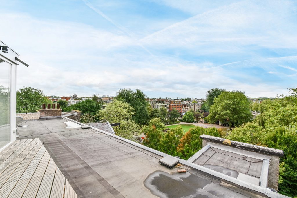 A flat roof of a building beside a park.