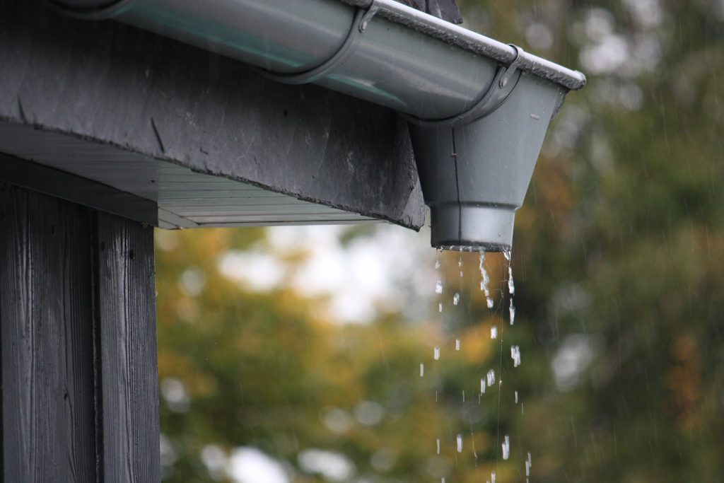 Water drips out of a downspout attached to a gutter system.